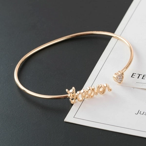 Golden open bangle bracelet with Forever inscription and sparkling rhinestone heart charm