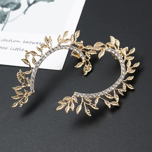Detailed view of gold-plated leaf ear cuff with sparkling crystals on black background