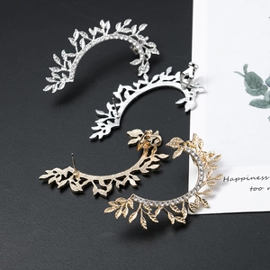 Detailed shot of sparkling hollow leaf earrings in gold and silver with rhinestones