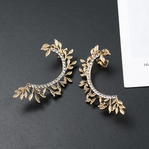 Macro view of gold leaf-shaped ear cuffs encrusted with sparkling white rhinestones