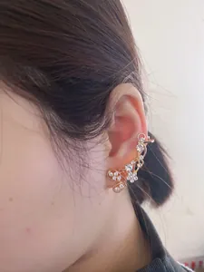 Gros plan d'un élégant ear cuff papillon doré serti de strass brillants sur l'oreille