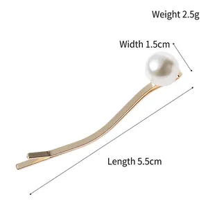 Golden wavy metal hair clip featuring a glossy white pearl accent on a plain background