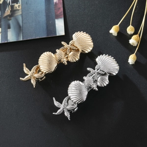 Golden and silver ocean starfish seashell metal hair clips set on grey textured surface