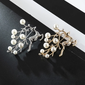 Detailed view of elk brooches with white pearls and sparkling crystals in gold and silver