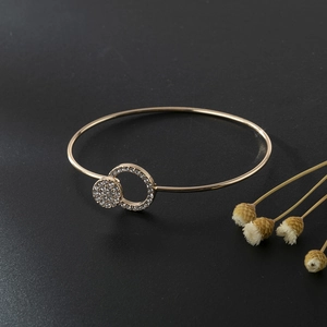 Macro shot of gold-plated bangle with interlocking diamond-encrusted circular rings