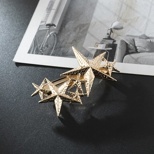 Golden alloy textured pentagram hair clip with layered stars on a sleek black surface