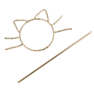 Detail of golden hollow cat hair slide with textured metal surface and matching hairpin