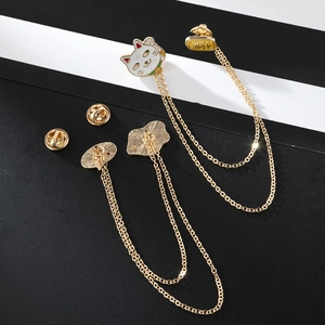 Detail of cartoon cat lapel pin with gold double chains and white enamel finish