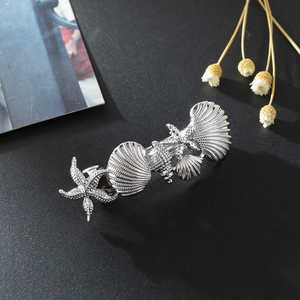 Detailed view of silver nautical hair clip with starfish and seashells on black background