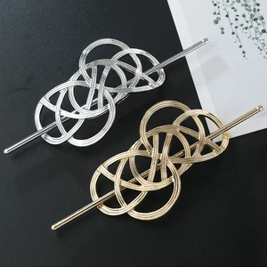 Detailed close-up of gold and silver geometric hollowed metal hair sticks on dark surface