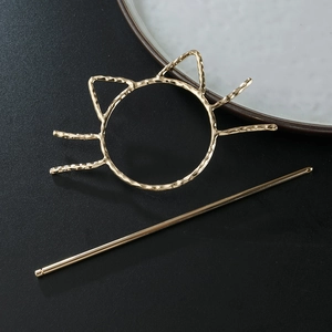 Golden hollow cat head hair pin with textured hammered finish on a dark background