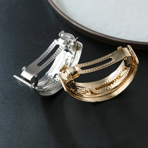 Textured gold and silver arched metal spring hair clips on a premium black background
