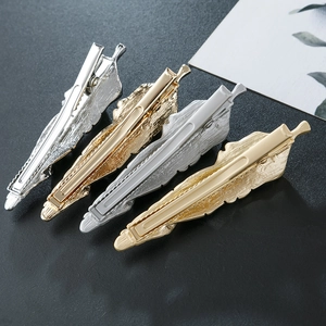 Close-up of four feather-shaped metal hair clips in gold and silver finishes