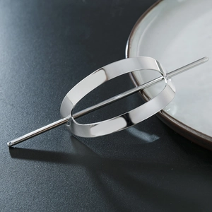 Minimalist silver oval hair cage with matching stick hair pin on elegant dark surface
