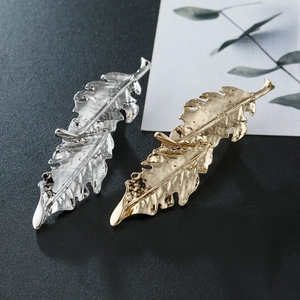 Detail of irregular leaf-shaped alloy hair clips in gold and silver with textured finish