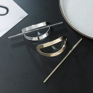 Detail view of oval hollow hair pins in gold and silver finish with polished metal texture