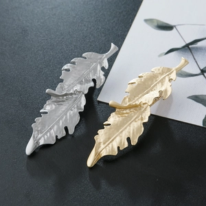 Detailed macro of gold and silver leaf hair clips with a unique matte metal texture finish