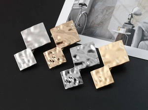 Detail showing geometric metal hair clips with textured hammered finish in gold and silver