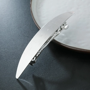 Detail of silver spring hair clip with brushed metal finish and sleek crescent design