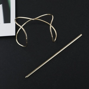 Ensemble d'épingle à cheveux en métal doré au design croisé sur un fond texturé noir