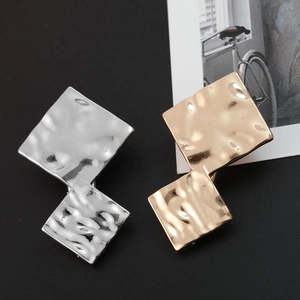 Detail of geometric metal hair clip with textured hammered finish in gold and silver