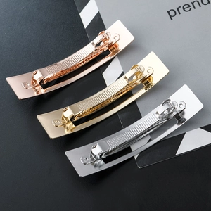 Minimalist metallic hair clips in rose gold, gold and silver finish on modern background