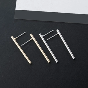 Minimalistische vertikale Stabohrstecker in poliertem Gold und Silber auf dunklem Grund