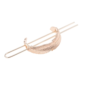 Detailed close-up of textured gold feather hair slide and matching metallic pin fastener