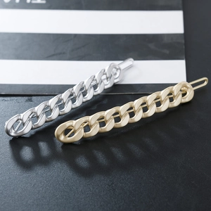 Detailed view of matte gold and silver chain hair clips on a textured background