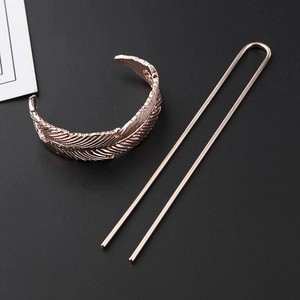 Detail showing a rose gold hollow carved feather hair accessory with U-shaped hair pin