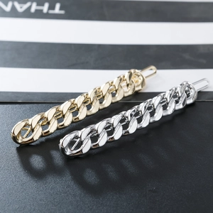 Detail showing polished gold and silver Cuban chain hair clips with a metallic mirror finish