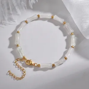 Dettaglio del bracciale con perle bianche a forma di bambù e chiusura dorata