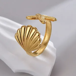 Elegant gold titanium steel open ring featuring a shell and starfish on a white pedestal