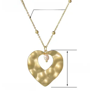 Detail of gold hammered heart necklace with pink pearl pendant and bead chain specs