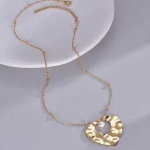 Elegant gold heart pendant necklace with pearl detail and hammered finish on jewelry chain