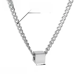 Close-up of polished silver square cube pendant on a minimalist stainless steel chain