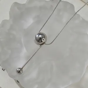 Detailed view of silver geometric pendant with snake chain on frosted surface