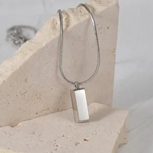 Minimalist silver stainless steel bar pendant necklace with sleek snake chain on stone
