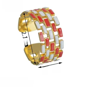 Detail view of gold-plated open ring with red and white enamel geometric patterns