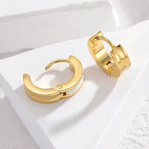 Minimalist gold hoop earrings with white enamel inlay on a modern marble pedestal