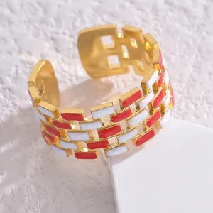Modern gold hollow open ring with red and white geometric enamel blocks on a white pedestal