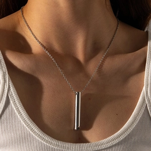Collana con ciondolo a fischietto minimalista in acciaio al titanio su canotta bianca