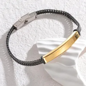 Détail d'un bracelet en corde tressée noire avec plaque dorée polie et boucle métallique