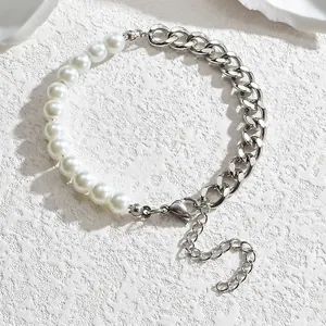Détail de la chaîne à maillons cubains et des perles blanches sur le bracelet en acier