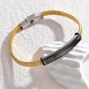Détail d'un bracelet tressé doré avec plaque courbée noire et fermoir argenté moderne