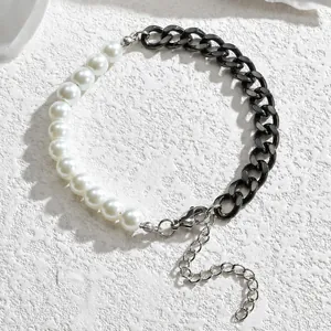 Détail d'un bracelet composé de perles blanches et d'une chaîne gourmette noire élégante