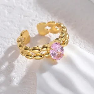 Vintage gold double-row beaded ring with a pink oval zircon stone on a white background