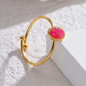 Minimalist gold open bangle with oval pink gemstone and textured metal bezel detail