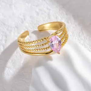 Detail view of gold beaded multi-layer ring featuring a pink pear-cut zircon stone