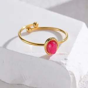 Minimalist gold adjustable ring with oval pink gemstone displayed on a white stone base